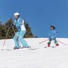 Niño con ropa de invierno aprendiendo a esquiar con su padre en la estación nevada . - foto de stock