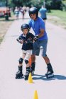 Senior teacher of rollerskating with boy practicing on class in park. — Stock Photo