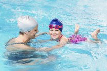 Усміхнена дівчинка розслабляється у воді і вчиться плавати з інструктором . — стокове фото