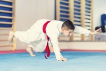 Menino treinando no tapete na aula de taekwondo . — Fotografia de Stock