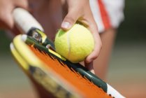Primer plano del jugador de tenis sosteniendo la pelota contra la raqueta . - foto de stock