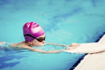 Menina na aula de natação com prancha de pontapé na água da piscina . — Fotografia de Stock