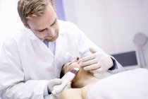 Schönheitstechniker behandelt Frau in Klinik mit Mikrodermabrasion im Gesicht. — Stockfoto