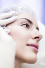 Técnico de beleza injetando botox no rosto feminino . — Fotografia de Stock