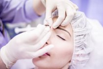 Beauty technician injecting botox into female face. — Stock Photo