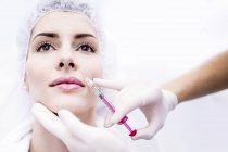 Young woman injecting botox injection on face, close-up. — Stock Photo