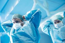 Surgeons gowning up in operating theatre. — Stock Photo