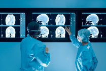 Cirujanos que observan imágenes por resonancia magnética (RM) escaneos cerebrales durante la cirugía cerebral. - foto de stock