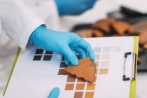 Mani dell'archeologo che confrontano i colori della ceramica con lo schema della cartella colori in laboratorio . — Foto stock