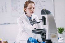 Portrait of young female archaeologist using microscope in laboratory. — Stock Photo