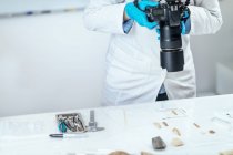 Female archaeology researcher documenting lithics with camera in laboratory. — Stock Photo
