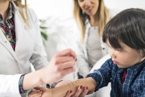 Pédiatre femme effectuant le test de piqûre de peau d'allergie sur le petit garçon avec la mère dans le bureau immunologiste . — Photo de stock