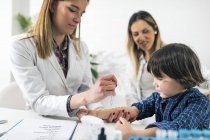 Doctora realizando prueba de alergia cutánea en un niño con madre en el consultorio de inmunología . - foto de stock