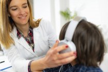 Ärztin setzt Jungen beim Hörtest Kopfhörer auf. — Stockfoto