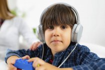 Junge trägt Kopfhörer als Hörtest, Ärztin legt Hand auf Kinderschulter. — Stockfoto