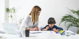 Boy coloring shapes with colorful pens for developmental psychology test in female doctor office. — Stock Photo