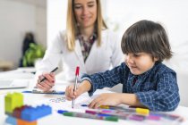 Хлопчик-дошкільнятко фарбує форми з барвистими ручками для тестування психології розвитку в офісі психолога. — стокове фото