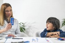 Niño en edad preescolar sometido a prueba de tarjetas lógicas para la prueba de psicología del desarrollo en la oficina de psicóloga femenina . - foto de stock