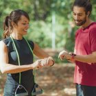 Young couple checking progress on smartwatches after outdoor training. — Stock Photo