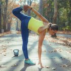 Woman stretching and bending while exercising in autumn park. — Stock Photo