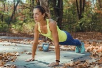 Femme faisant de l'exercice de planche haute tandis que l'entraînement par intervalles de haute intensité à l'extérieur . — Photo de stock