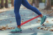Low section of woman exercising with resistance band in park. — Stock Photo