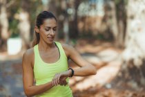 Woman checking progress on smartwatch after outdoor training in autumn park. — Stock Photo