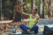 Frau macht Selfie nach Training im Freien im Herbstpark. — Stockfoto