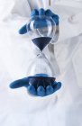 Reloj de arena en manos de científicos, imagen conceptual del paso del tiempo . - foto de stock