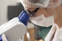 Asistente de laboratorio con microscopio polarizante en laboratorio microbiológico . - foto de stock