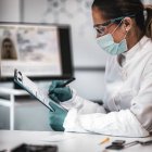 Experta en ciencia forense digital femenina tomando notas durante la investigación . - foto de stock