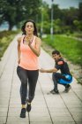 Jovem mulher exercitando maratona de corrida no parque com personal trainer . — Fotografia de Stock
