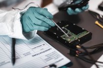 Close-up of digital forensic expert examining computer hard drive in police science laboratory. — Stock Photo