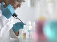 Scientist pipetting sample into micro centrifuge tubes ready for automated analysis. — Stock Photo