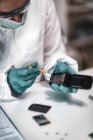 Perito forense da polícia examina telefone celular confiscado em laboratório de ciências . — Fotografia de Stock