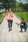 Young woman exercising running marathon in park with personal trainer. — Stock Photo