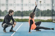 Mujer joven deportista haciendo ejercicio al aire libre con entrenador de fitness personal . - foto de stock