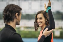Personal fitness trainer coaching young smiling woman doing resistance band exercise. — Stock Photo