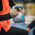 Hands of sporty woman lifting kettlebell while training outdoors. — Stock Photo