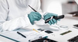 Esperto forense della polizia che esamina il cellulare confiscato nel laboratorio scientifico . — Foto stock
