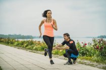 Mujer joven haciendo ejercicio corriendo maratón por el río con entrenador personal . - foto de stock