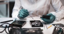 Experta forense digital femenina examinando disco duro de computadora con equipo electrónico en laboratorio de ciencia policial . - foto de stock