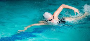 Giovane donna nuotare in piscina coperta acqua . — Foto stock