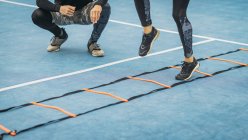 Legs of woman exercising with personal fitness coach using agility ladder. — Stock Photo