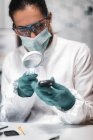 Police forensic analyst examining with magnifying glass confiscated mobile phone. — Stock Photo