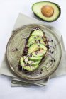Healthy vegan snack of fresh avocado on toast with sprouts on round plate. — Stock Photo