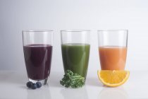Gläser mit frischen Säften aus Beeren, Orange und Grünkohl. — Stockfoto