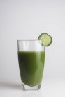 Bicchiere di succo verde fresco con una fetta di cetriolo . — Foto stock
