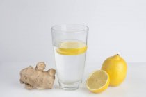 Un vaso de agua con rodajas de limón fresco y jengibre . - foto de stock