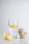Стакан воды со свежими ломтиками лимона и имбирем . — стоковое фото